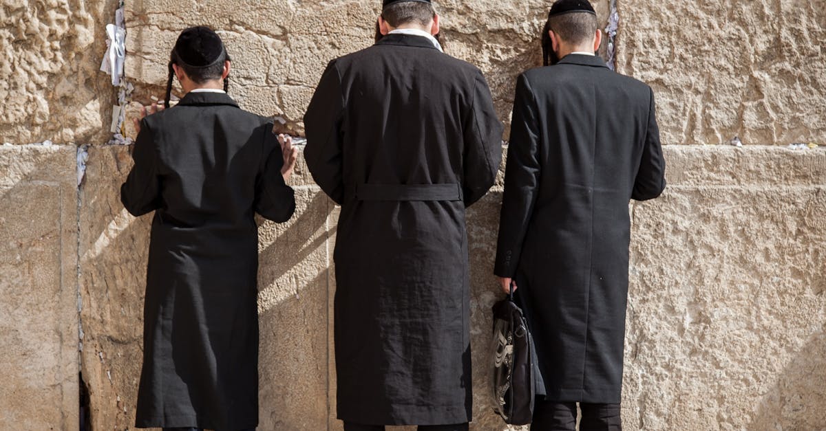 Orthodox Jewish men facing the Western Wall in Jerusalem, deep in prayer and contemplation.